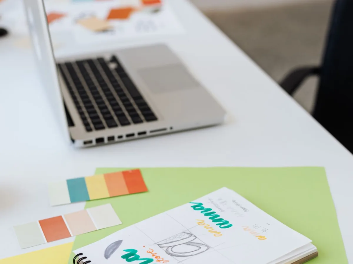 Laptop, muestras de color y materiales de diseño sobre un escritorio