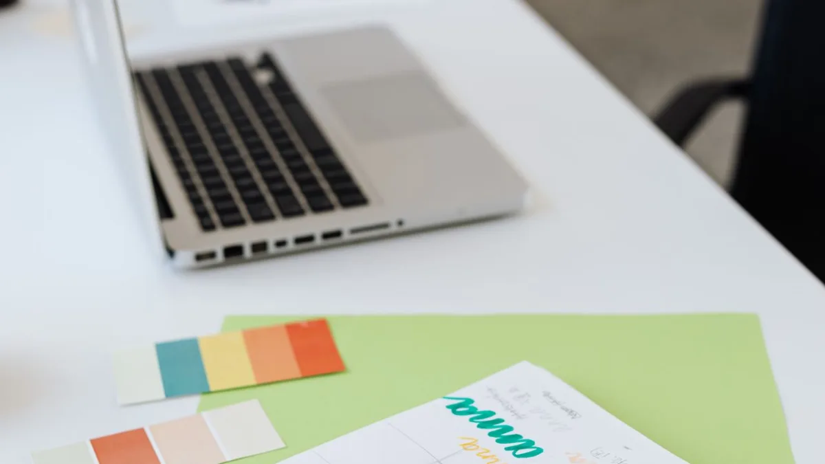 Laptop, muestras de color y materiales de diseño sobre un escritorio