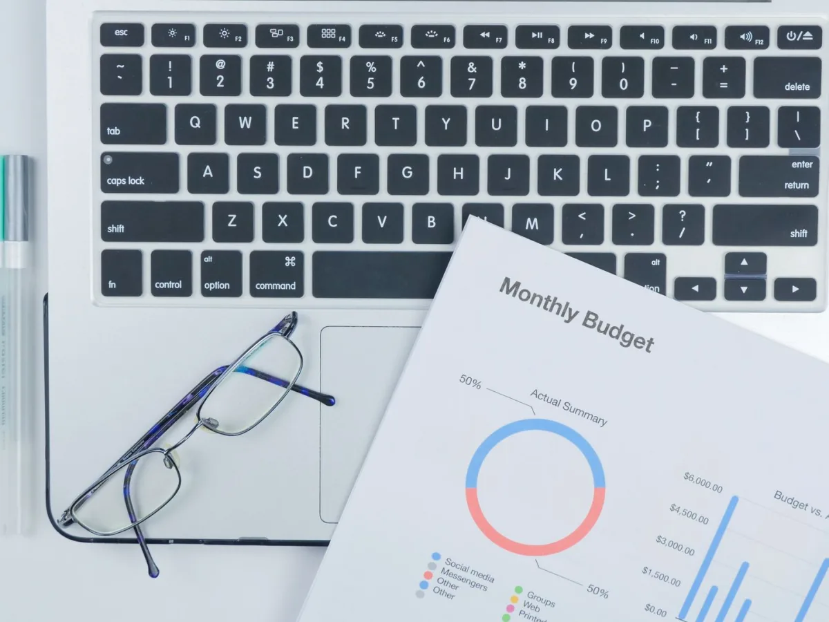 Laptop, lentes y un presupuesto con gráficos sobre un escritorio